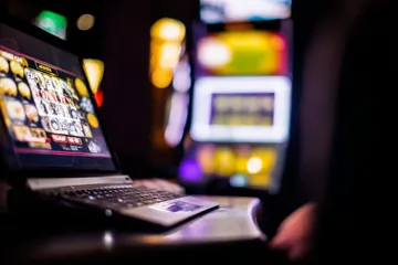 A woman smiling by bright slot machines showing lucky symbols, showcasing the exciting slot offerings at VM916.